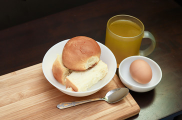 breakfast with buns, half-boiled egg and orang juice isolated on dark wooden table.  A healthy breakfast concept