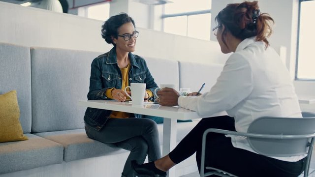 HR manager talking with a female employee in the cafeteria. Businesswoman giving feedback to her employee.
