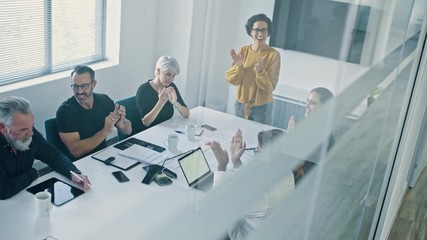 Businesspeople clapping hands after a successful brainstorming session in the boardroom. Group of men and women applauding after a productive meeting.
