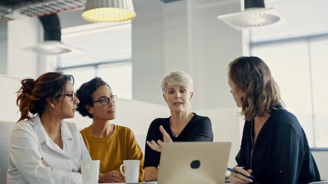 Senior businesswoman explaining and briefing new markering strategy to her team in a meeting. Multi-ethnic business group planning in a meeting.
