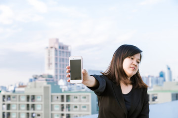 Business asian women wear black smart suit with smartphone on top of building