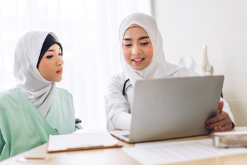 Muslim asian female doctor consulting and check up information on laptop computer with muslim woman in hospital.woman has sick.healthcare and medicine