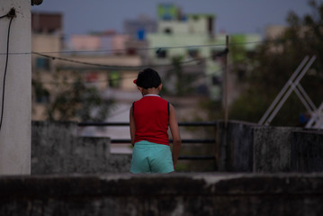 An Indian Bengali cute little girl is playing on rooftop with a water pipe for gardening during the lock-down of corona virus outbreak. Indian lifestyle and home isolation 