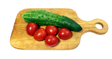 Tomatoes and cucumbers on a wooden cutting board isolated.