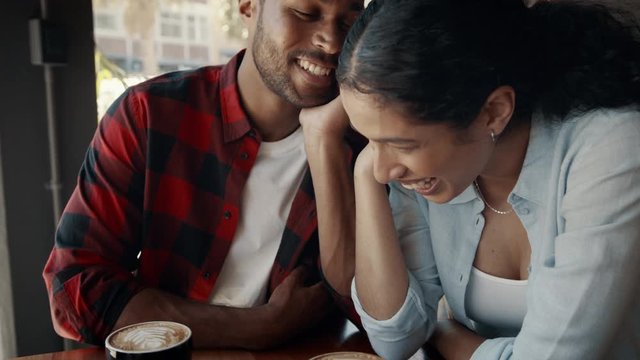 Happy young couple enjoying dating in a coffee shop. Man and woman talking and smiling while sitting at a cafe table. 
