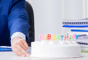 Young businessman celebrating birthday alone in office