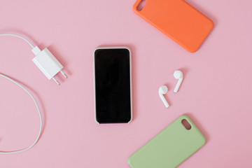 Top view of a smartphone with headphones and charge and silicone cases.