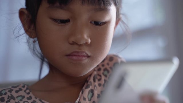 child play with mobile phone while staying home