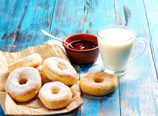 Homemade donuts with a mug of milk on a wooden in a blue background