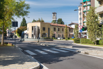 Fototapeta na wymiar Traffic roundabout preceded by a pedestrian crossing on a road in a typical Italian town. Somma Lombardo (street Milano), Lombardy, northern Italy 