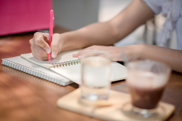 A woman writes with a pencil on a notebook at home. Women who work outdoors at home