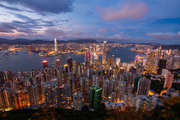 Panorama view of an urban metropolitan city at night with dense cityscape and tall illuminated skyscrapers during sunset in Asia