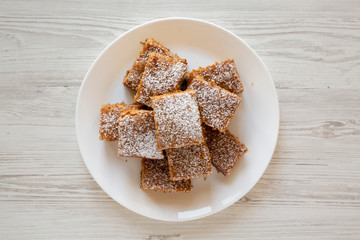 Homemade Tasty Applesauce Cake on a white plate on a white wooden table, top view. Flat lay, from above, overhead.