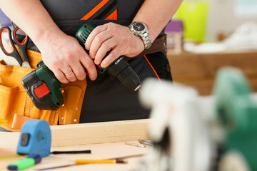 Arms of worker using electric drill closeup. Manual job, DIY inspiration, improvement job, fix shop, yellow helmet, joinery startup idea, industrial education, profession career concept