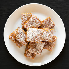 Homemade Applesauce Cake on a white plate on a black background, top view. Flat lay, from above, overhead. Close-up.