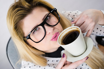 Happy woman at office drinking hot coffee