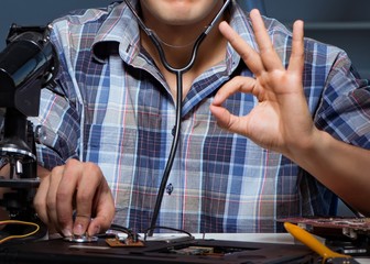 Computer repair concept with man inspecting with stethoscope