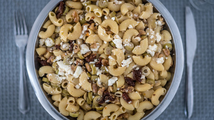 Top view of an isolated delicious pasta salad on a dining table background with a fork and knife
