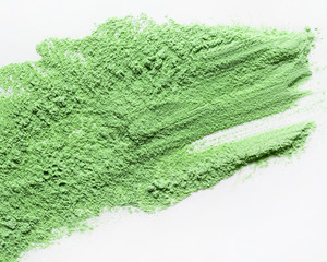A top view of a loose green cosmetic or food powder pigment on a white background. Colorful...