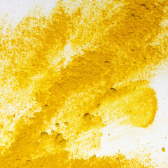 The loose yellow cosmetic or food powder ingredient on white background. Curcuma or turmeric spice. Colorful texture of pigment. Copy space. Close-up. Top view