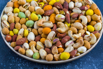 Nuts in bowls on the table, almonds, cashews and coasted nuts on the blue background.