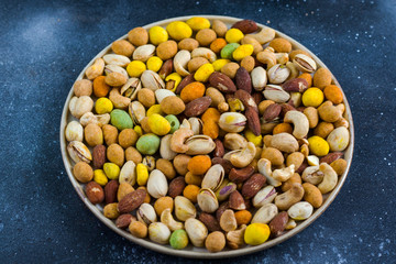 Nuts in bowls on the table, almonds, cashews and coasted nuts on the blue background.