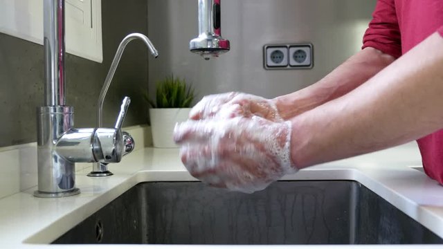Side view of a hands in a sink washing with soap.