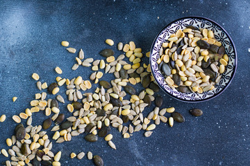 Sunflower and pumpkin seeds  in bowl on the blue background.  Large group of seeds. Snack and appetizer. 