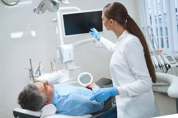Fototapeta premium Female dentist consulting male in office stock photo