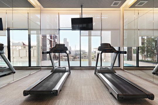 Treadmill Equipment In Modern Gyms Fitness With City And Sky View, On Big Glass Window Background