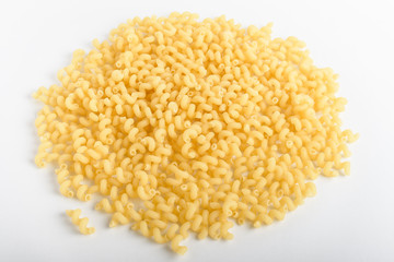 Heap of dried serpentelli Italian pasta in a round bowl ready to be cooked, isolated on a white table, top view or flat lay of healthy food 
