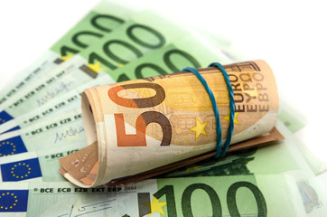 50 euros twisted into a roll on a background of 100 euros. White background.