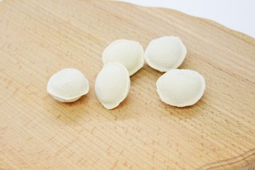 Frozen raw dumplings located on a wooden board