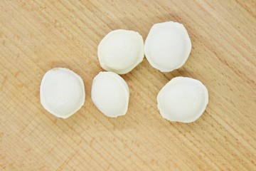 Frozen raw dumplings located on a wooden board