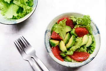 Avocado grapefruit salad with lettuce in a bowl on grey metal background. Raw vegetarian detox salad, healthy food. Selective focus