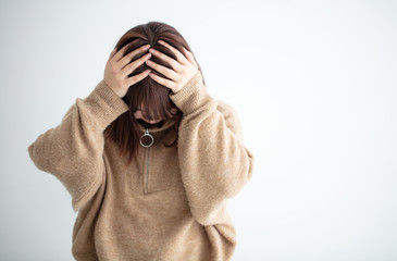 私服の女性が頭を抱えている　悲しい　sad