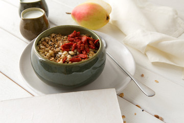 healthy breakfast on the table - granola with goji berries, yogurt, pear and mandarin