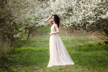 beautiful bride in a wedding dress on a background of blooming gardens, spring photo shoot