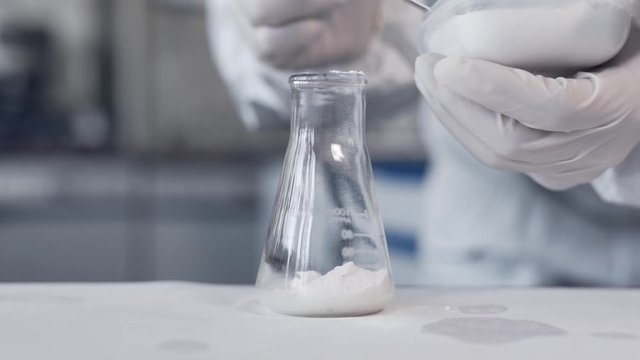 closeup of white powder poured into the lab into a test tube