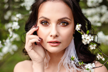 Closeup portrait of a beautiful young bride in a wedding dress in blooming gardens, wedding photo session