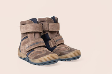 Brown leather stylish children's shoes, boots isolated on beige background, close-up. Baby clothes 