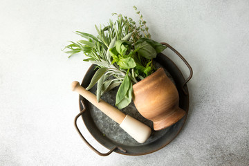 fragrant herbs in a wooden mortar on a gray background