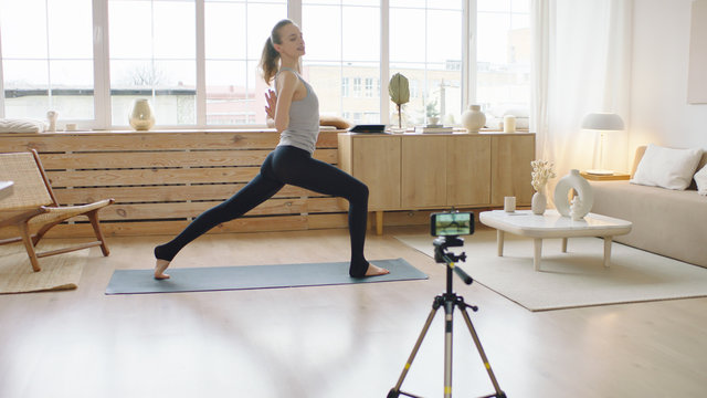 Attractive Caucasian recording making live stream or vlog about doing yoga at home. Stay home, quarantine workout