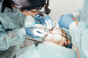 Dentists will perform an operation, implant placement. Real operation. Tooth extraction, implants. Professional uniform and equipment of a dentist. Healthcare Equipping a doctor’s workplace. Dentistry