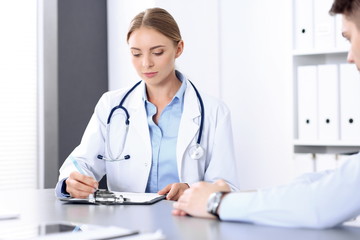 Doctor and patient in clinic. Beautiful blonde physician consulting business man about his health. Medicine concept