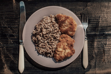 Chicken schnitzel with buckwheat on plate over wooden background. Top view, flat lay.