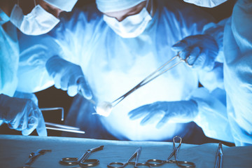 Group of surgeons wearing safety masks performing operation. Medicine concept