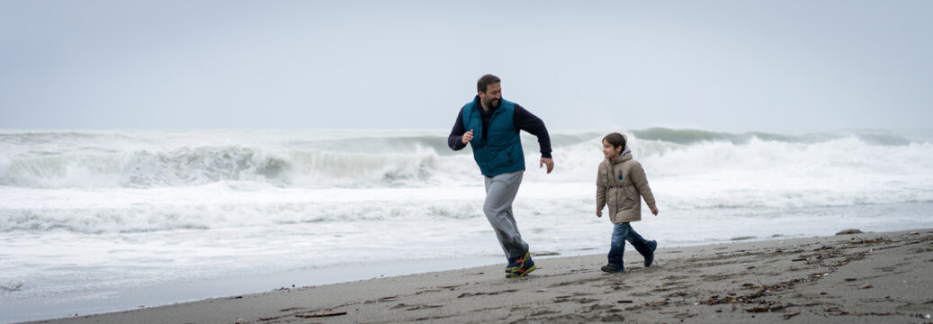 Father and son having fun on winter beach