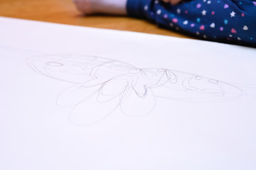 kids hobby. child draws sketch crown with a pencil on white paper