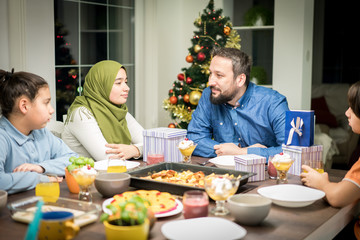 Fototapeta na wymiar Muslim interreligious family with christmas tree in background